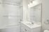 The James Apartments | Bright bathroom featuring a white vanity, large mirror, and bathtub with a white tiled shower and curtain. | Luxury Apartments Haverhill MA