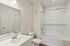 The James Apartments | Modern bathroom featuring a white vanity with a large mirror, toilet, and bathtub with a tiled shower. | Luxury Apartments Haverhill MA