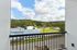 The James Apartments | Private balcony with a railing, offering a scenic view of green hills, rooftops, and a playground area in the distance. | Luxury Apartments Haverhill MA