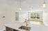 The James Apartments | View of an open living space from a kitchen island with pendant lighting, featuring large windows with a scenic view and hardwood flooring. | Luxury Apartments Haverhill MA