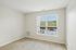 The James Apartments | Unfurnished bedroom with beige carpeting, a large window, and a view of rooftops and green hills. | Luxury Apartments Haverhill MA