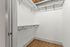 riverwalk lofts | An empty walk-in closet with white walls, wooden flooring, and metal shelves along the sides. An exposed duct runs across the ceiling. | apartments with walk in closets lawrence ma