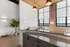 riverwalk lofts | Spacious loft apartment with brick walls and large windows. Sleek kitchen with a dark countertop and modern fixtures. Bright, airy living area with a potted plant and cozy seating. Contemporary decor and ample natural light. | luxury apartments for rent near boston