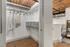 riverwalk lofts | A walk-in closet with a wooden floor and exposed wood ceiling. It contains metal shelving with woven baskets, a few hanging clothes, and a white railing on the right. The space is well-lit and industrial in style. | luxury loft apartments near boston