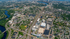 Aerial view of a vibrant cityscape featuring a river, a lush green park, and well-organized neighborhoods.