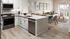 Open kitchen and living room with white cabinetry, modern appliances, and bright seating area.