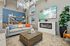Chic living room with modern decor, featuring a stylish fireplace, large TV, and cozy seating with colorful cushions.