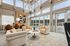 Bright and airy contemporary lounge with large windows, stylish beige seating, and a modern art piece.