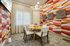 Stylish dining room featuring a round wooden table, elegant chairs, modern pendant light, geometric wall art, and vibrant patterned wallpaper.