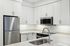 Sleek modern kitchen featuring stainless steel appliances, elegant white cabinetry, and a stylish quartz countertop with an integrated sink.