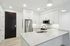 Modern kitchen with sleek white cabinetry, stainless steel appliances, and elegant quartz countertops under stylish pendant lighting.