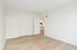Bright and inviting empty room with sleek hardwood floors and a glimpse into a modern kitchen, offering endless decorating possibilities.