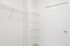 Contemporary apartment with spacious white closet and modern shelving, perfect for organized living.