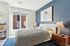 Bright and inviting bedroom with modern decor, featuring a cozy bed, sleek nightstand, and large window for natural light.