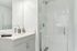 Elegant bathroom with a modern glass-enclosed shower and sleek vanity, accented by a stylish faucet and decorative orchids.