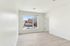 Bright, airy bedroom with large window and inviting view, featuring sleek flooring and modern design.
