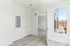 Bright minimalist room with sleek hardwood floors, open doorway, and expansive window view for natural light.