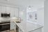 Modern open-plan kitchen with sleek white cabinetry, high-end appliances, and bright windows offering a scenic view.