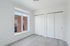 Bright and airy room with large windows, sleek wooden flooring, and spacious white closets, offering modern elegance.