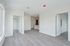 Modern open space with sleek hardwood floors, ample natural light, and a glimpse of a cozy kitchen area.