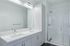 Modern bathroom design featuring a sleek double sink vanity and a luxurious glass-enclosed shower with stylish white tiles.