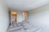 Bright, spacious room with plush carpet, highlighting two doors leading to a closet and a cozy kitchen area.