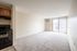 Bright, spacious apartment with plush carpeting, modern kitchen, and large sliding glass doors leading to a private balcony.