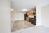 Bright, open kitchen with sleek black appliances and rich wooden cabinetry, offering a welcoming entrance to comfortable apartment living.