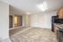 Inviting open-concept apartment interior with seamless transition from kitchen to carpeted living area, featuring modern appliances and bright natural lighting.