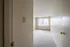 Bright and inviting bedroom with soft carpet flooring, large window with vertical blinds, and neutral wall colors.