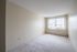 Bright and spacious bedroom with soft carpet and large window with blinds, offering a serene and comfortable living space.