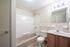 Bright and inviting bathroom featuring a clean bathtub, modern vanity, and soft lighting.