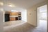 Bright apartment with an open kitchen featuring modern appliances, warm wooden cabinetry, and a cozy adjoining living area.