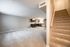 Bright and spacious open-concept living area with modern kitchen and inviting stairway, perfect for comfortable living.