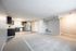 Modern open-plan living space with sleek kitchen featuring stainless steel appliances, dark cabinetry, and bright natural lighting.
