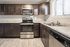 Modern kitchen with stainless steel appliances, sleek dark wood cabinets, and ample counter space, illuminated by natural light through large windows.