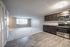 Modern open-plan apartment featuring elegant kitchen cabinetry and spacious living area with carpet and hardwood floors.