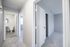Bright and inviting hallway leading to a modern bathroom and cozy bedroom, showcasing a clean and elegant design with soft carpet and natural lighting.