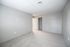 Spacious and bright empty room with soft carpet flooring and neutral gray walls, featuring an open closet and a hint of natural light streaming in.