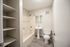 Modern bathroom featuring a sleek tub, elegant pedestal sink, and convenient built-in shelving.