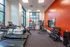 Bright and modern fitness center featuring treadmills, stationary bike, weights, and vibrant orange accent wall.