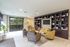 Inviting modern apartment lounge featuring cozy seating, elegant built-in bookshelves, and large windows with lush green views.