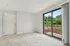 Inviting living space with plush carpet, sliding glass doors, and a beautiful garden view, perfect for relaxation.