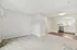 Bright and airy living space with plush carpet, adjacent to a modern kitchen featuring white cabinetry and stainless steel appliances.