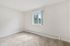Bright and spacious room with fresh carpet and a large window offering serene outdoor views.
