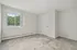 Bright, spacious bedroom with plush carpeting and large window with serene tree view, offering comfort and tranquility.