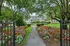 Charming garden entrance leading to a picturesque apartment building, surrounded by vibrant flowers and lush greenery.
