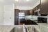 Princeton Westford Apartments | 	Modern kitchen in an apartment in Westford, MA with dark wooden cabinets, stainless steel appliances including a refrigerator, stove, and microwave, plus granite countertops with a double sink. White tile backsplash and bright overhead lighting. | One bedroom apartments in westford