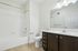 Elegant bathroom featuring a pristine white bathtub, sleek vanity with ample storage, and contemporary lighting fixtures.