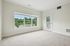 Princeton Westford Apartments | Bright, empty room with beige carpet, light-colored walls, large window overlooking greenery, and a glass door to a small balcony—perfect for your apartment in Westford MA. | Apartments with Balcony in Westford